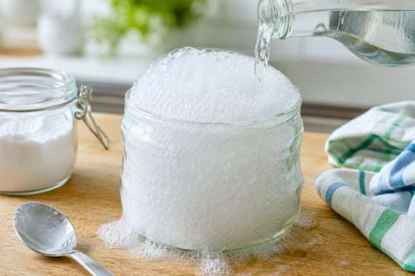 Vinaigre versé sur du bicarbonate avec une mousse débordante.