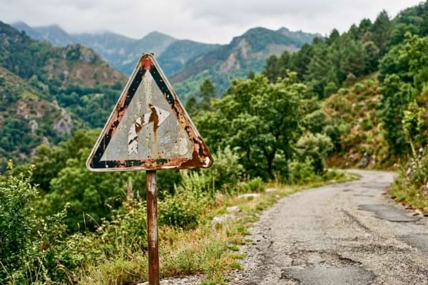 un panneau de signalisation de virage dangereux us&eacute; par le temps