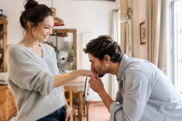 Homme embrassant la main d’une femme dans un intérieur chaleureux