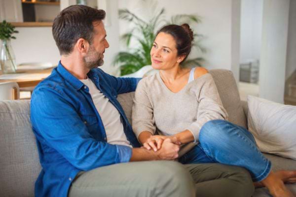 Couple assis sur un canapé se tenant la main avec complicité