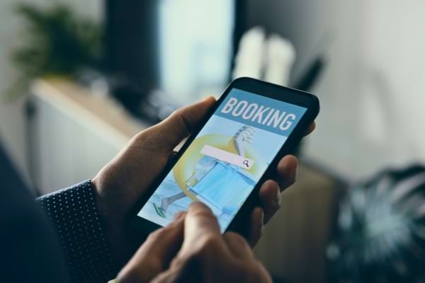 Un homme r&eacute;serve ses billets d'avion sur smartphone