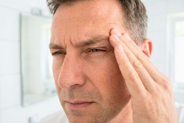 Homme se tenant la tempe avec douleur intense