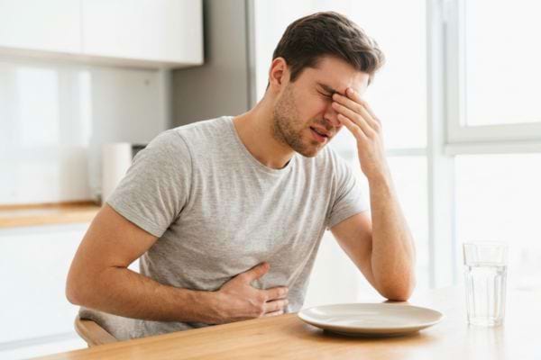 Homme naus&eacute;eux se tenant le ventre &agrave; table
