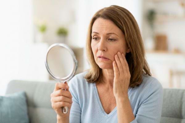 Femme inqui&egrave;te regardant son visage dans un miroir
