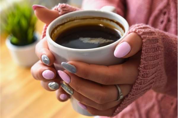 Une tasse de café entre les mains d'une personne