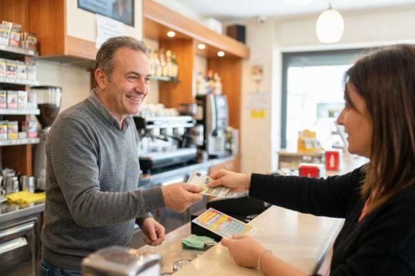 Cliente payant un buraliste au comptoir avec des billets en main