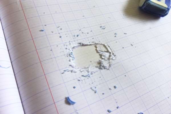 Un cahier d'&eacute;cole aux lignes Sey&egrave;s avec un trou d&eacute;chir&eacute; au milieu de la page