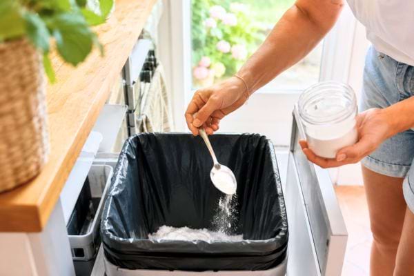 Personne versant du bicarbonate au fond d&rsquo;une poubelle propre