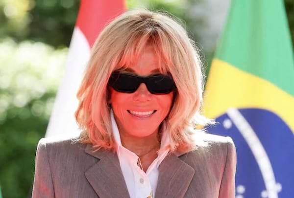 Brigitte Macron souriante avec des lunette devant le drapeau du Br&eacute;sil et de l France