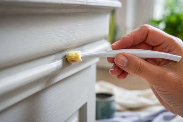 Retouche précise d’une moulure peinte avec une brosse à dents et un embout en éponge.