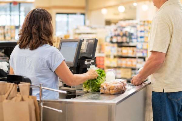 Caissi&egrave;re en caisse classique avec un client et des courses