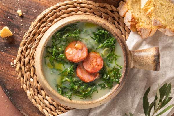 un bol de terre cuite avec du caldo verde, du chorizo et du pain