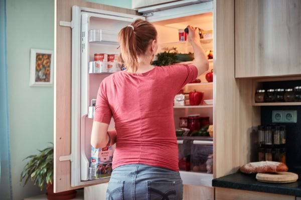 une femme est devant son frigo ouvert