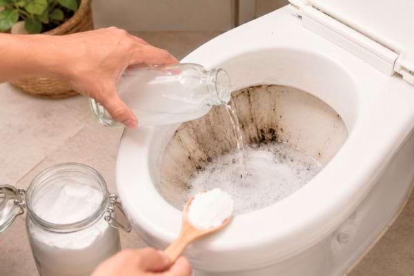 Vinaigre blanc et bicarbonate versés dans des toilettes tachées.