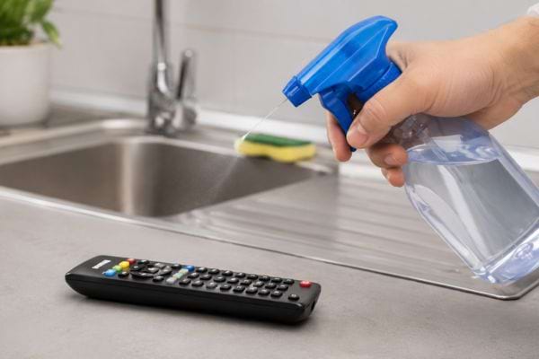 Main qui pulvérise un spray près d’une télécommande, l’erreur à éviter pour ne pas l’abîmer