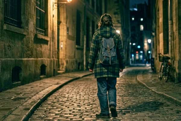 une jeune femme de dos, vêtue d'un manteau des années 90, marchant rapidement et anxieusement dans une rue