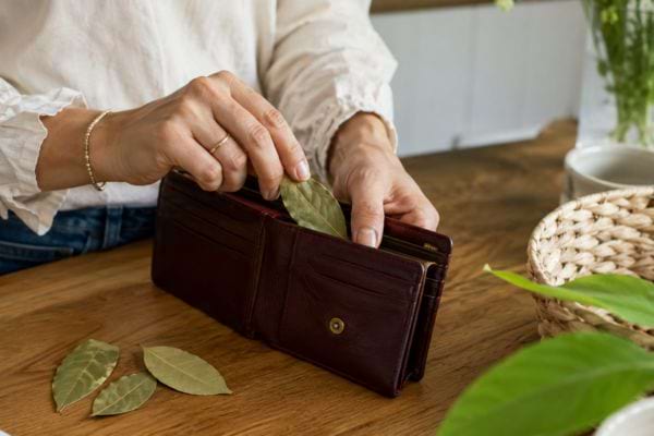 Femme plaçant une feuille de laurier dans son portefeuille sur une table