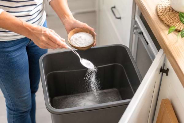 Ajout de bicarbonate dans une poubelle pour renouveler l&rsquo;astuce anti-odeurs