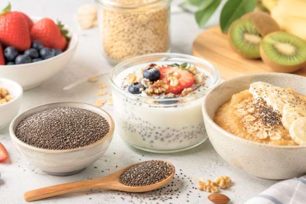 Bol de graines de chia avec yaourt, fruits frais et porridge sur une table de cuisine.