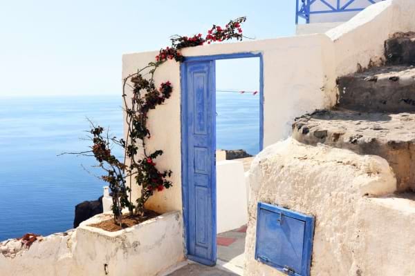 vue sur la mer à partir d'une rue blanche avec une porte bleue entrouverte