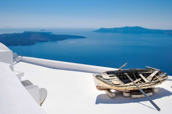vue sur la mer et les îles à partir d'une terrasse blanche avec un vieux bateau en bois