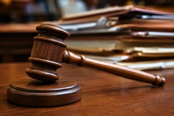 un lourd marteau de juge en bois massif posé sur un bureau en chêne