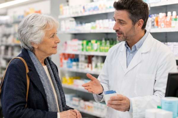 Pharmacien conseillant une senior sur les vaccins recommand&eacute;s