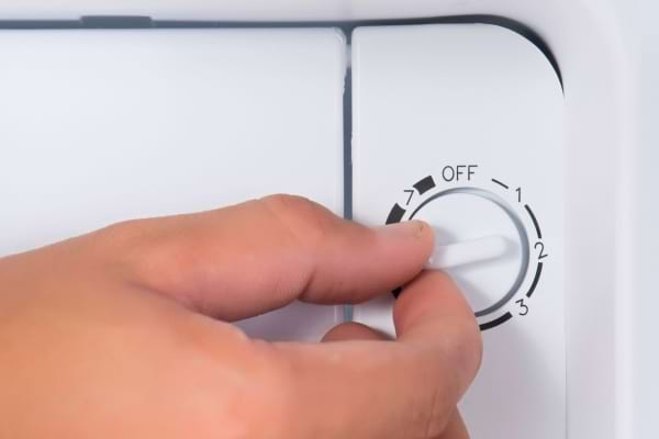 Une personne règle le thermostat d'un frigo