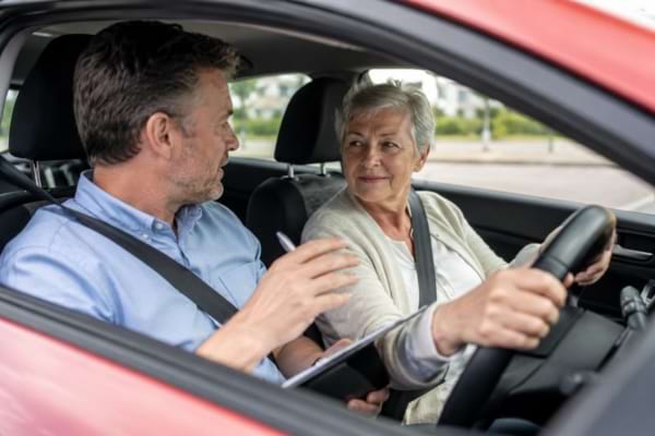 moniteur d'auto-école discutant calmement avec un conducteur senior dans une voiture moderne
