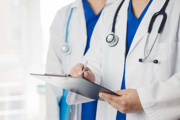 deux m&eacute;decins en blouse blanche avec un dossier de patient