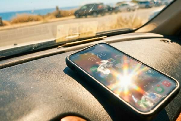 Un téléphone oublié sur le tableau de bord d'une voiture en plein soleil estival
