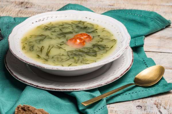 une assiette blanche de caldo verde avec du chorizon sur une serviette verte