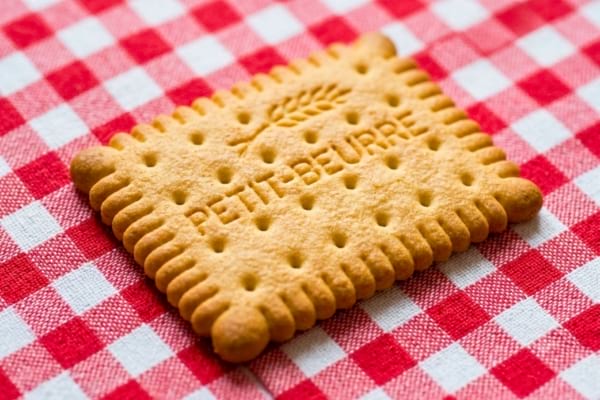 un biscuit Petit Beurre pos&eacute; sur une nappe &agrave; carreaux rouges et blancs.