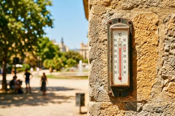 un thermom&egrave;tre ext&eacute;rieur affichant une temp&eacute;rature tr&egrave;s &eacute;lev&eacute;e, accroch&eacute; &agrave; un mur en pierre,