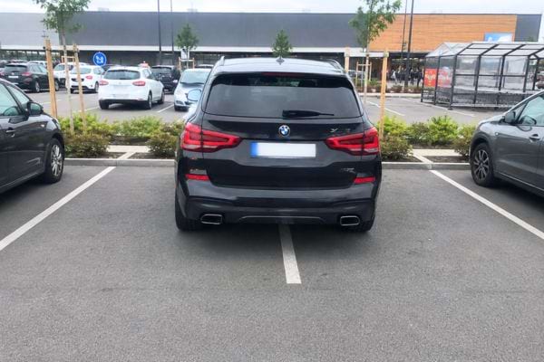 voiture noire gar&eacute;e sur deux places de parking