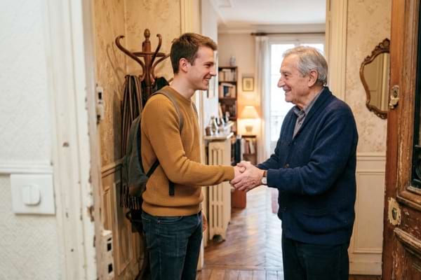 Deux personnes, un homme âgé et un jeune adulte, se serrant la main