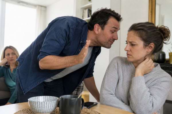Homme parlant sèchement à une femme mal à l’aise à table