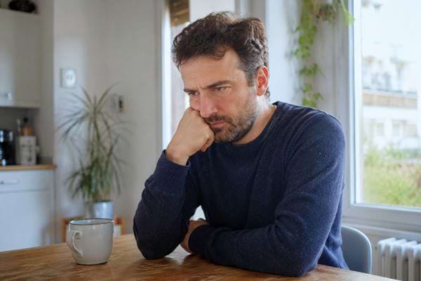 Homme pensif et inquiet assis seul dans une cuisine
