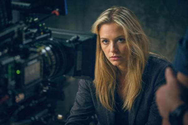 une jeune actrice blonde au regard intense et sérieux, éclairage sombre