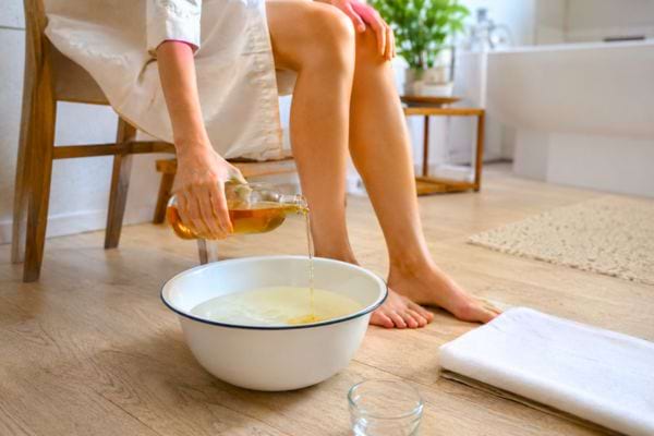 Vinaigre de cidre versé dans une bassine pour préparer un bain de pieds