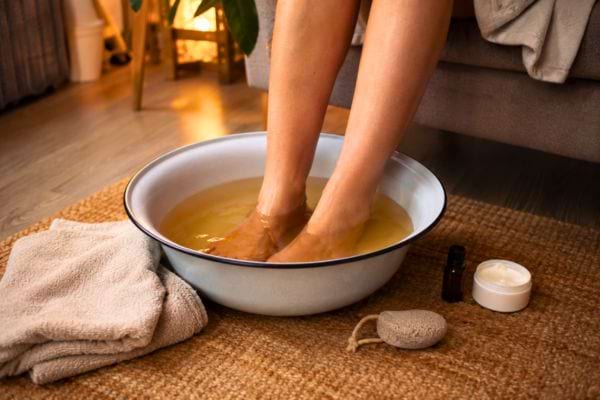 Pieds trempant dans un bain au vinaigre de cidre avec serviette et soin