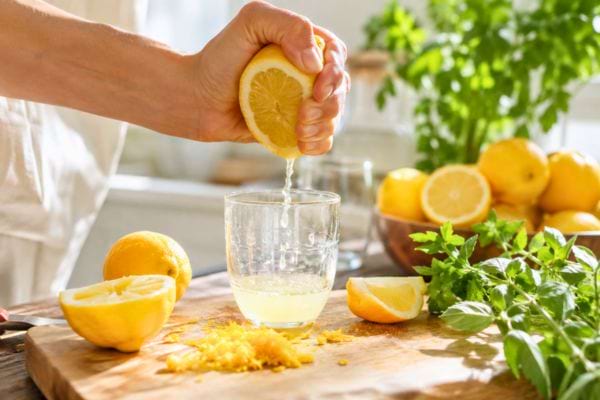 Main pressant un citron frais dans un verre en cuisine