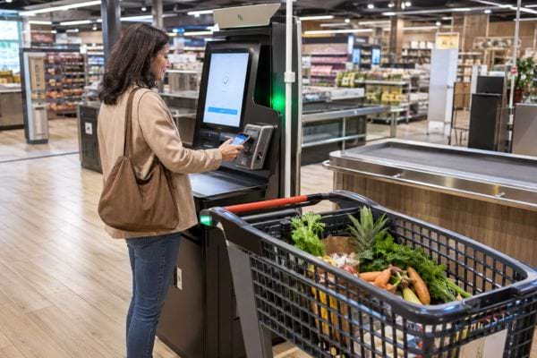 Cliente payant ses courses à une borne sans vider son chariot connecté.