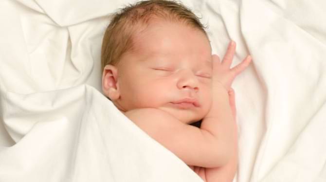 un b&eacute;b&eacute; gar&ccedil;on dort dans un lange blanc
