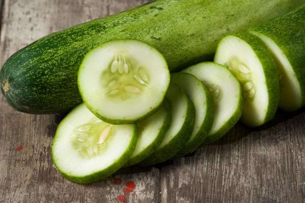 Le concombre posé sur une table avec des tranches de concombres coupées