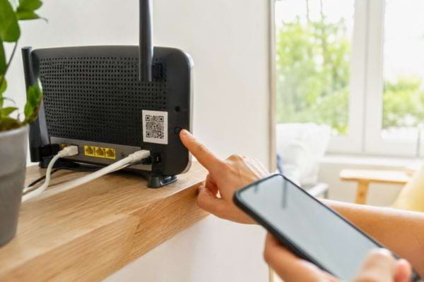 Une personne repère le QR code au dos de la box pour connecter son smartphone au Wi-Fi.