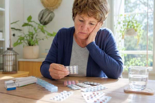 Femme examinant plusieurs médicaments pour dormir, inquiète de leurs effets sur sa mémoire.