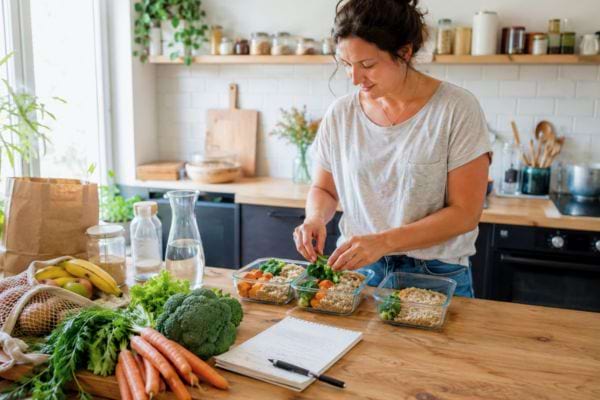 Femme préparant plusieurs repas maison à l’avance pour réduire ses dépenses alimentaires.