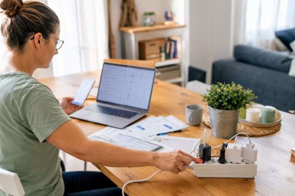 Femme débranchant une multiprise pour économiser de l’électricité au quotidien.