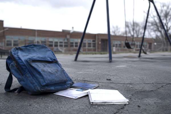 un cartable bleu et des cahiers abandonnés dans une cours d'école
